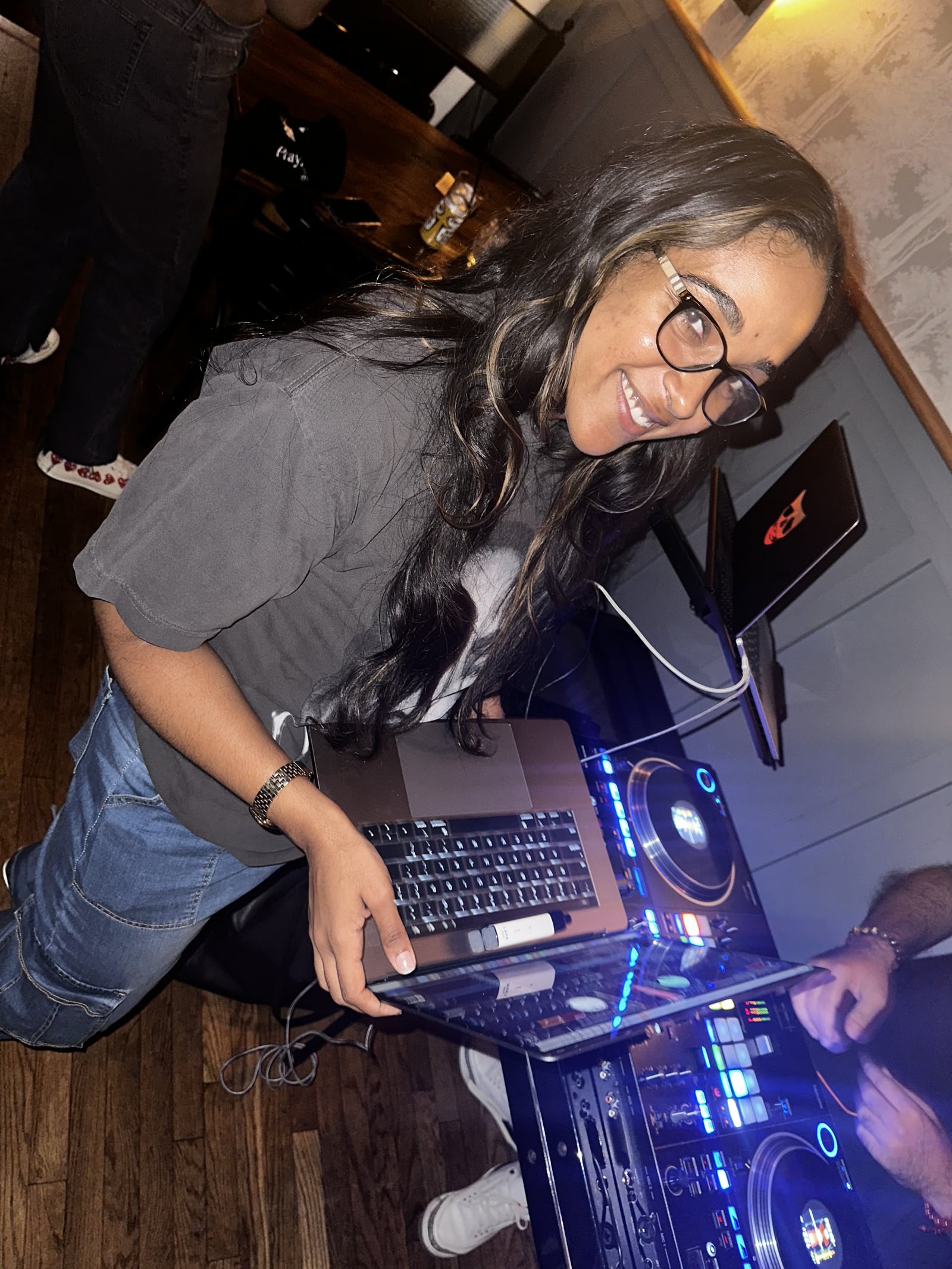 La Phiesa leaning over the CDJs at Woodlot's June night, laughing up at the camera while the decks glow blue beneath her.