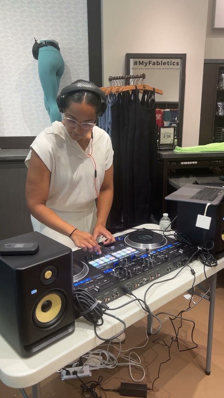 La Phiesa heads-down in the mix on the controller at Fabletics, KRK monitors flanking the pop-up booth.