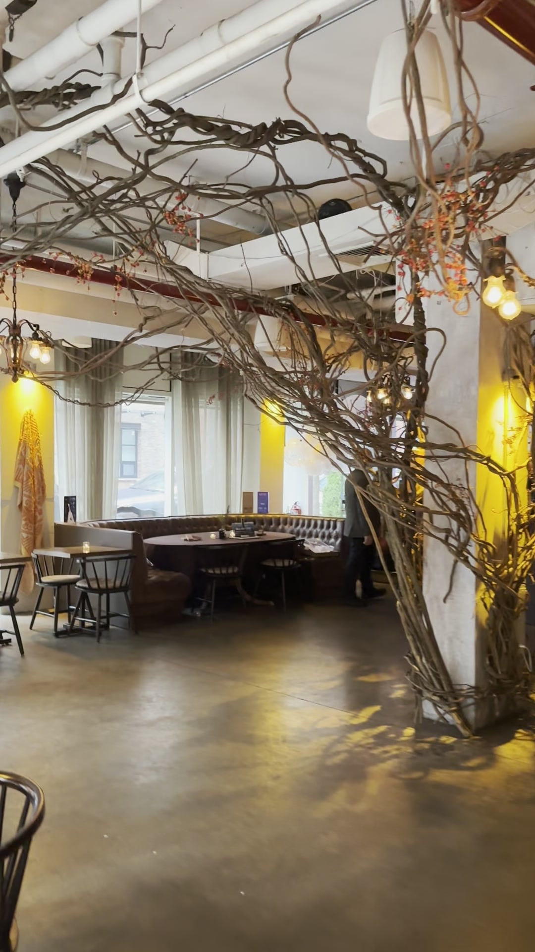 The PAX room before doors, branch sculptures and warm bulbs strung over the banquettes