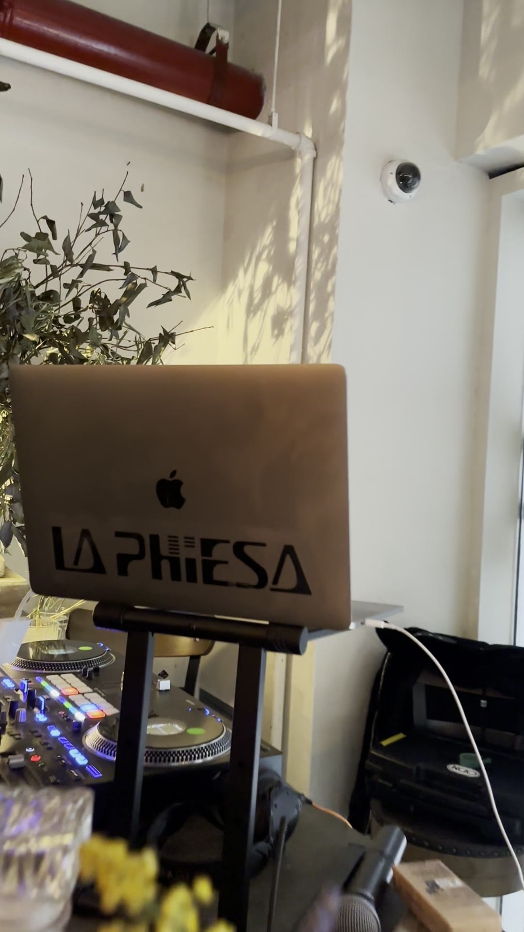 The La Phiesa laptop perched above the turntables at PAX, afternoon light across the wall