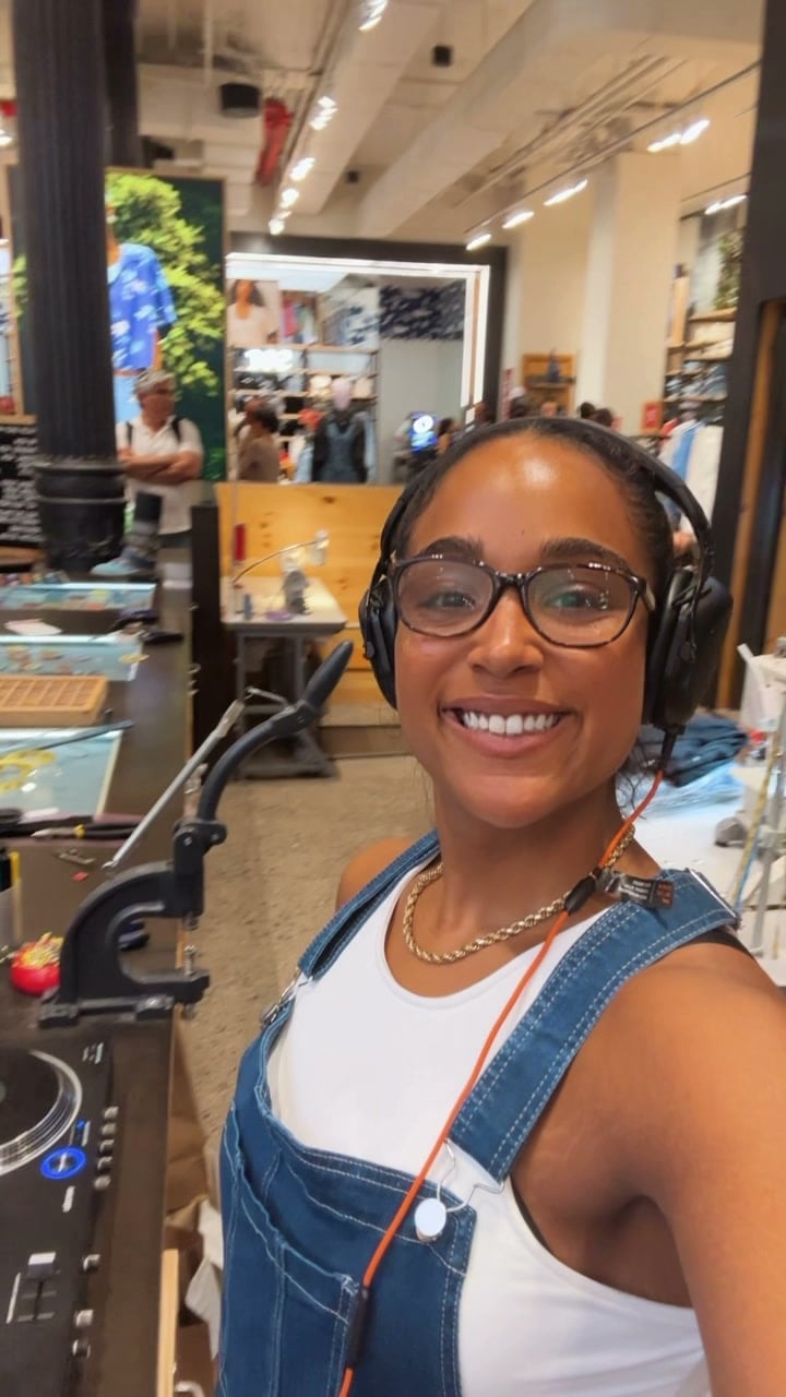 La Phiesa grinning between tracks at the Levi's SoHo store, the in-store tailor shop benches visible behind her
