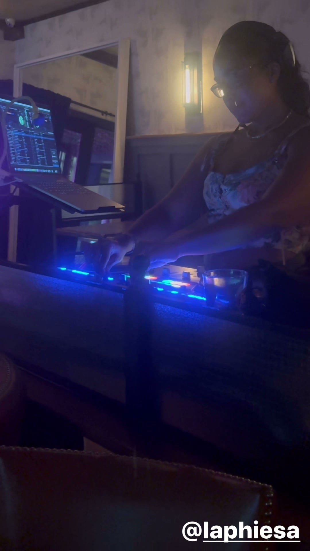 La Phiesa working the mixer at Woodlot on a May night, laptop and blue booth lights glowing beside her.