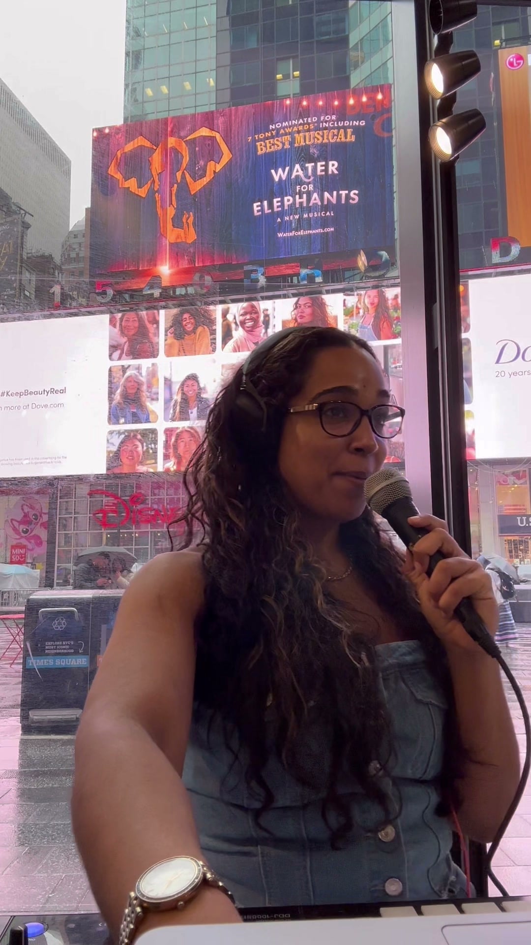 La Phiesa on the mic behind the decks at the Levi's Times Square store, Times Square billboards and neon glowing through the window behind her