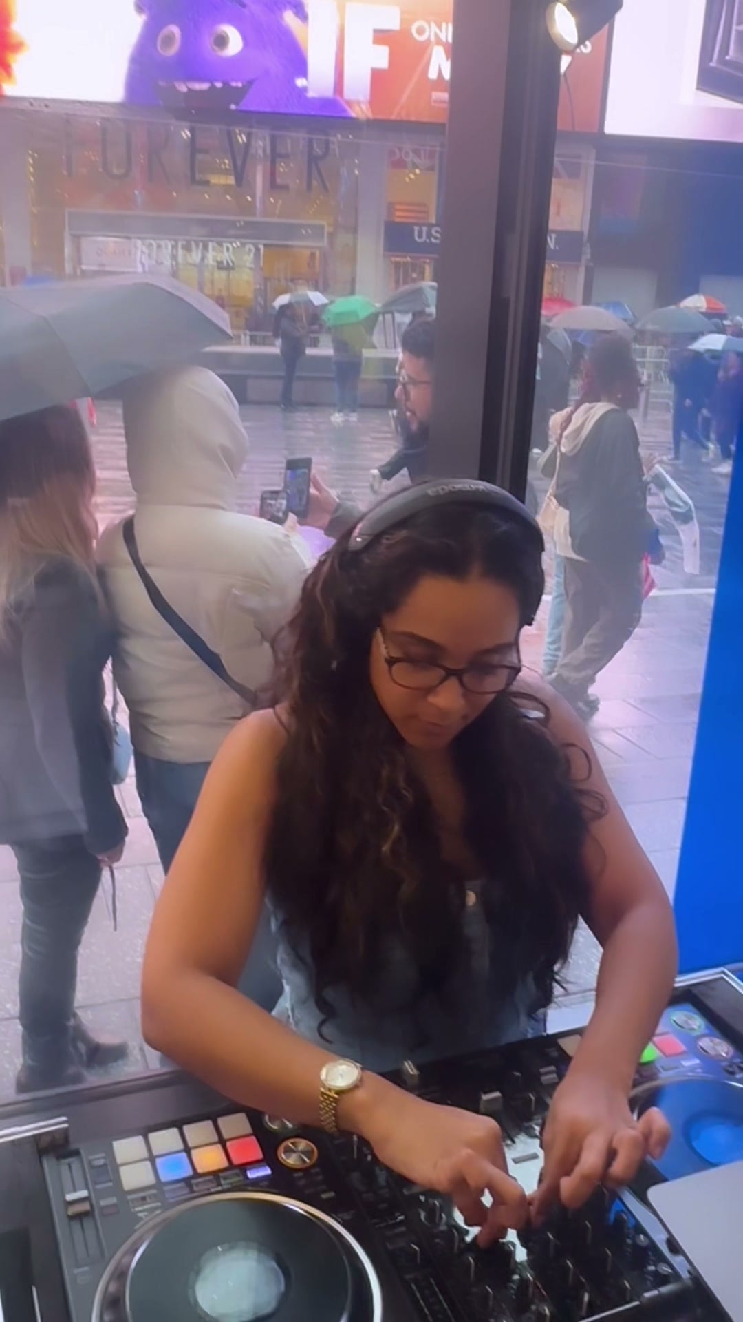 La Phiesa mixing at the Levi's Times Square storefront window while a rain-soaked Times Square crowd watches from under umbrellas
