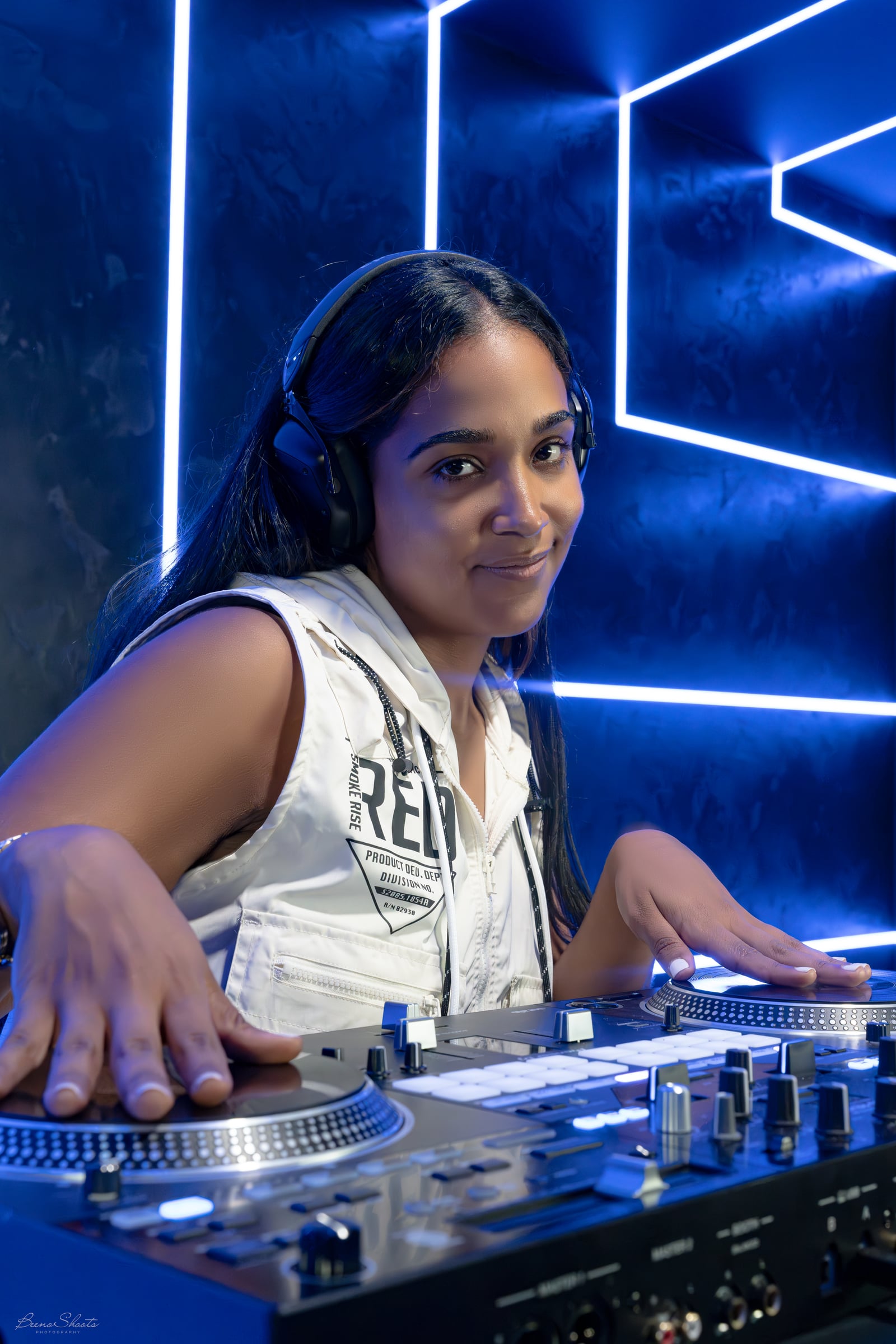 La Phiesa leaning over the turntables under blue light, looking to camera