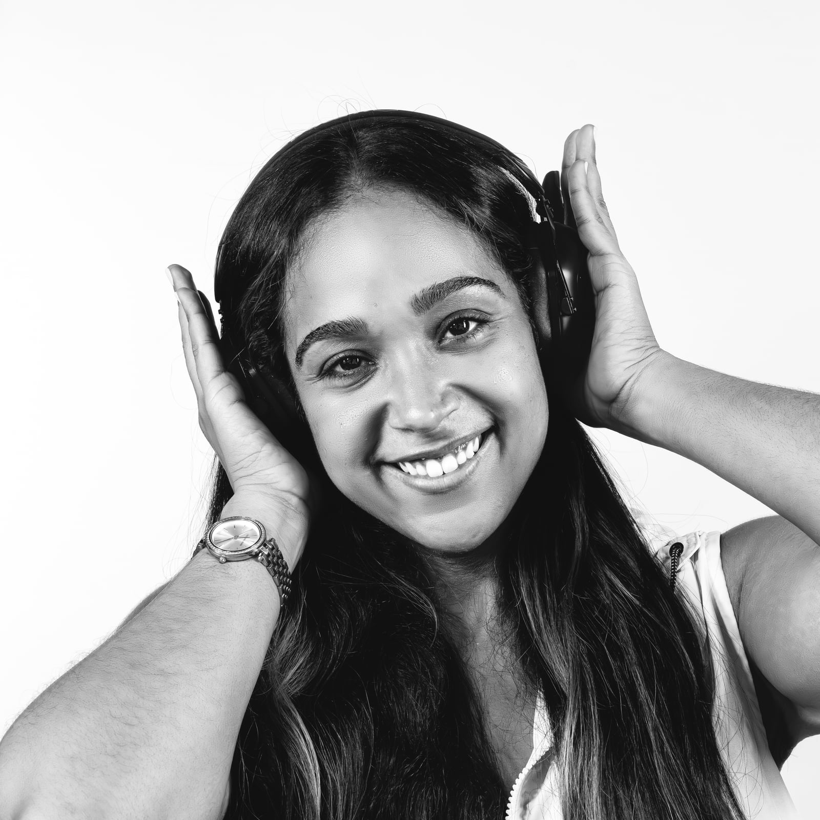 Black-and-white close-up of La Phiesa smiling, both hands cupping her headphones