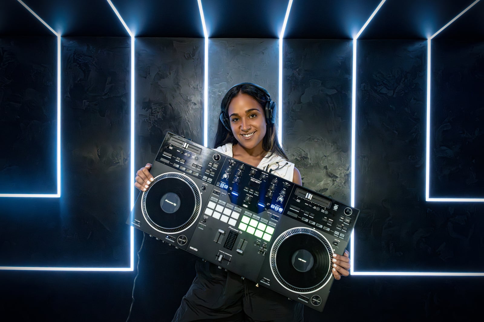La Phiesa holding her DJ controller up to the camera, blue neon frame behind