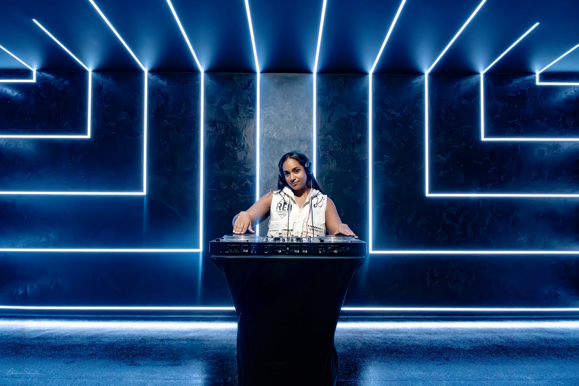 La Phiesa at the booth, framed by a symmetrical maze of blue neon light